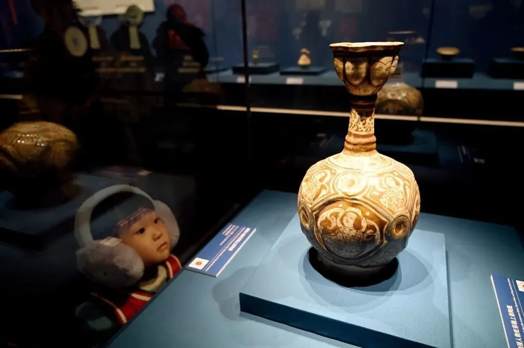 2025年12月20日，“流动的星河——波斯文化艺术瑰宝展”在内蒙古博物院开展。图为公元12—13世纪的“细颈人物虹彩釉上彩陶瓶”。摄影/本刊记者刘文华